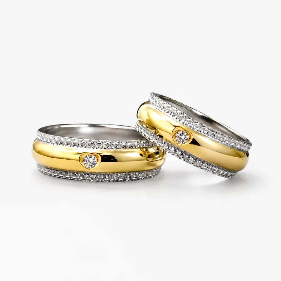 Coppia di fedi bombate in oro bicolore 18 kt con bordi diamantati e diamante incastonato
